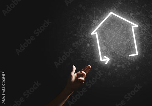 Conceptual image with hand pointing at house or main page icon on dark background