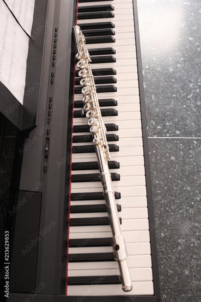 classic music concept: transverse flute rest on a piano keyboard