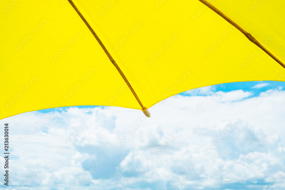 Colorful yellow fabric umbrella with blue sky cloud with copy space.