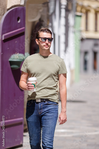 Happy young urban man drinking coffee in european city outdoors