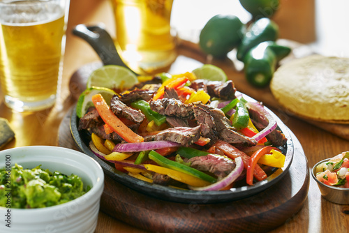 mexican beef fajitas in iron skillet with guacamole and beer