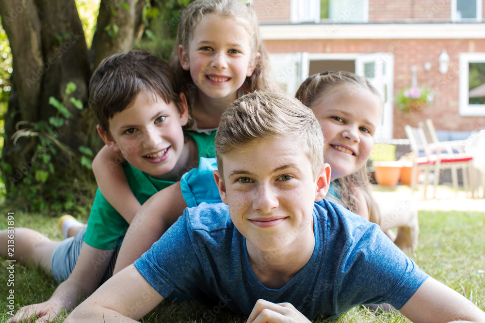 Portrait Of Four Brothers And Sisters Lying In Garden At Home Portrait Of Four Brothers And Sisters Lying In Garden At Home