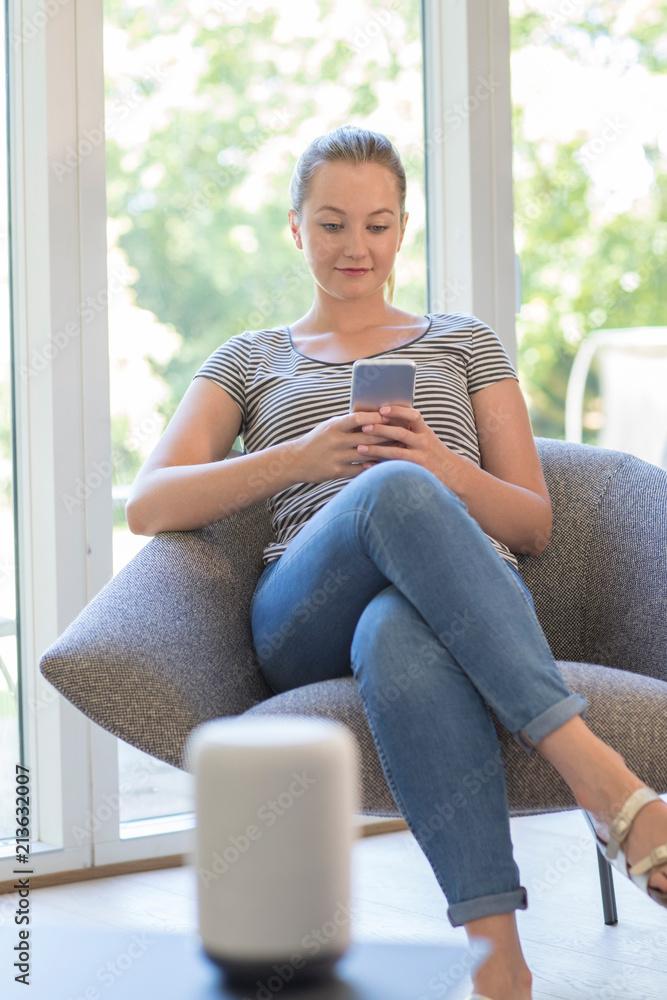 Obraz premium Woman Streams Music From Mobile Phone To Wireless Speaker