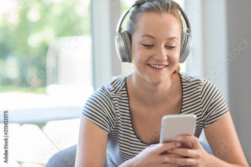 Woman At Home Streams Music From Mobile Phone To Wireless Headphones