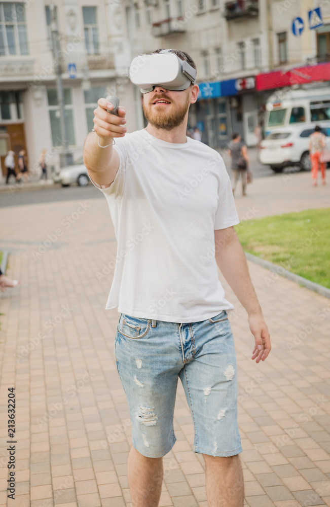 A young man plays a game wearing virtual reality glasses on the street. A young man plays a game wearing virtual reality glasses on the street.