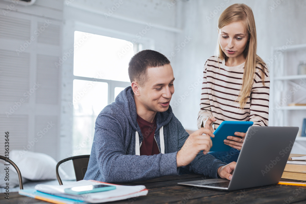 Obraz premium Communicating. Inspired blond girl holding her tablet and the man sitting at the table