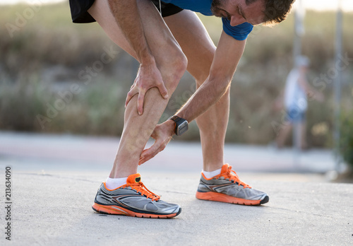 Runner touching painful twisted or broken ankle.