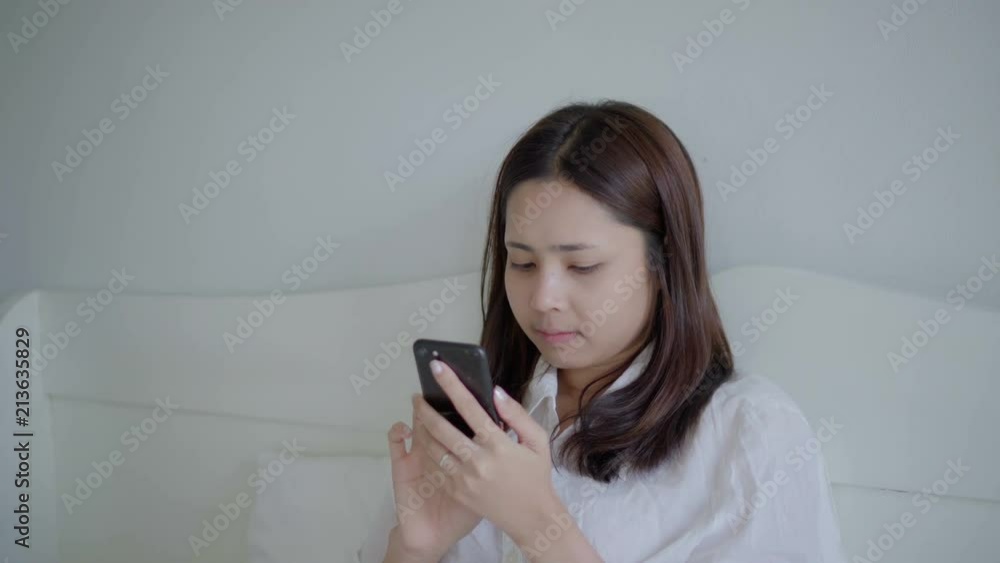 Young asian woman using smartphone on bed after wake up in morning. Young asian woman using smartphone on bed after wake up in morning.
