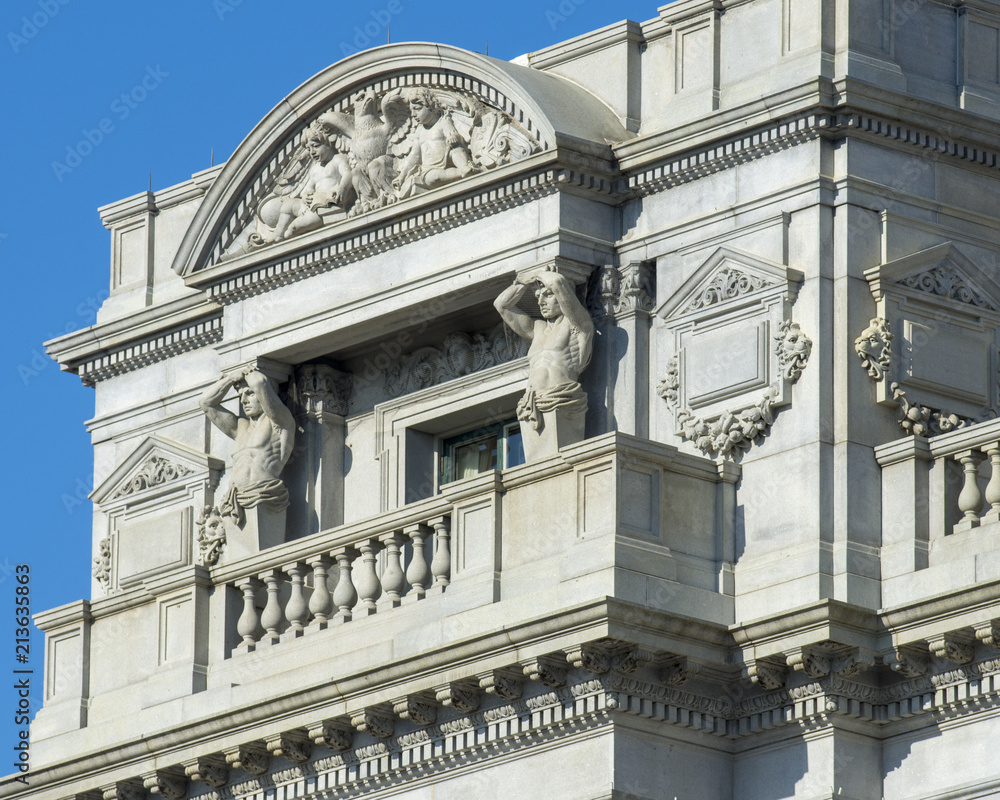 Fototapeta premium Statues of nude male figures hold up a window pediment at the Thomas Jefferson Building of the Library of Congress in Washington DC.