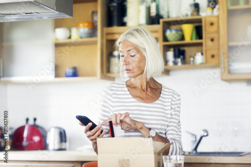 Ältere Frau mit päckchen und smartphone und Geldkarte