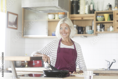 Ältere Frau mit Schürze kochend © SundGo