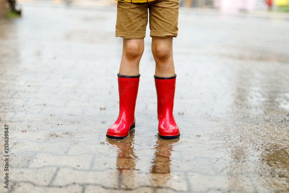 Child wearing red rain boots jumping into a puddle. Child wearing red rain boots jumping into a puddle.