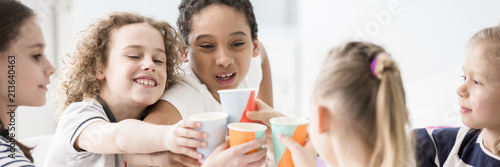 Canvas Print Group of happy children drinking juice from paper cups and having fun during a c