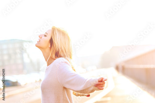 young woman outdoor back light arms raised laughing - freedom, victory, satisfaction concept