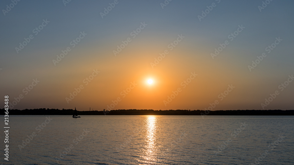 Sonnenuntergang an einem See, Silhouette eines Segelboots