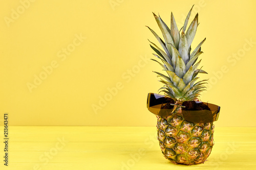 Hawaiian ananas in sunglasses and copy space. Fresh tropical fruit and text space. Beach and tropical concept.