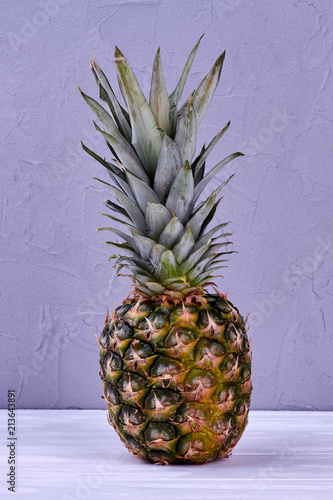 Fresh pineapple on wooden background. Pineapple with green leaves on light wood. Healthy tropical fruit.