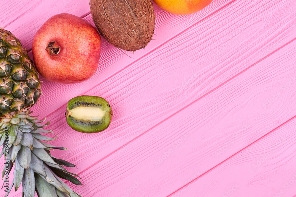 Fototapeta premium Colorful tropical fruits and copy space. Border from exotic fruits on pink wood and text space. Benefits of organic food.