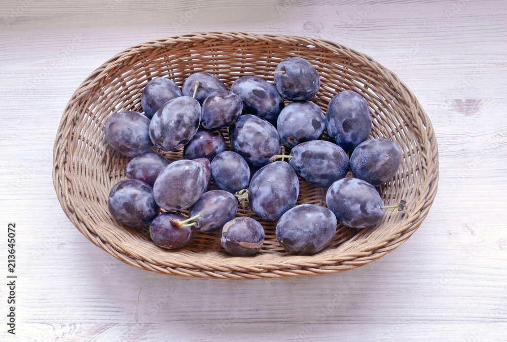 Fototapeta premium fresh prunes lie in a wicker basket