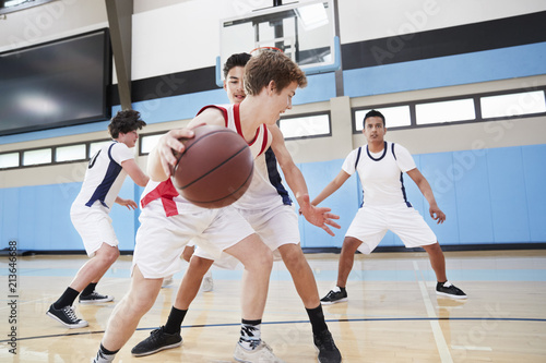 Male High School Basketball Team Dribbling Ball On Court © Monkey Business