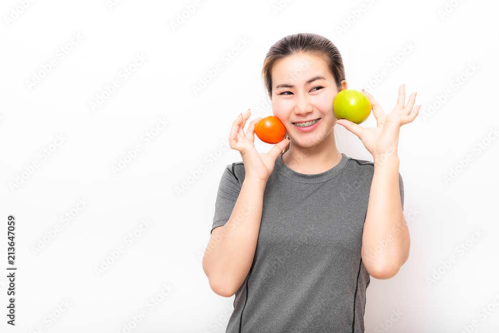 woman with dental braces having fun with tomato and green apple on white background woman with dental braces having fun with tomato and green apple on white background