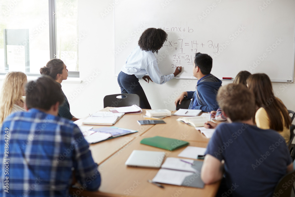 Female High School Tutor At Whiteboard Teaching Maths Class Female High School Tutor At Whiteboard Teaching Maths Class