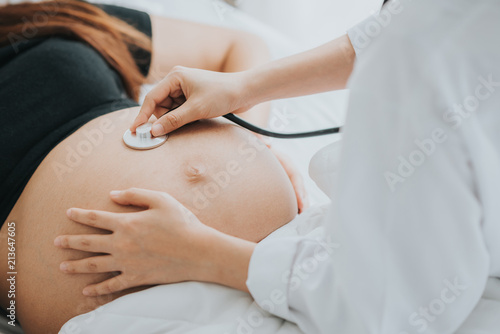 Fototapeta doctor use stethoscope to check baby heartbeat in pregnant belly