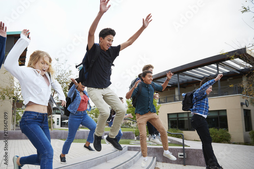 Group Of High School Students Jumping In Air Outside College Buildings