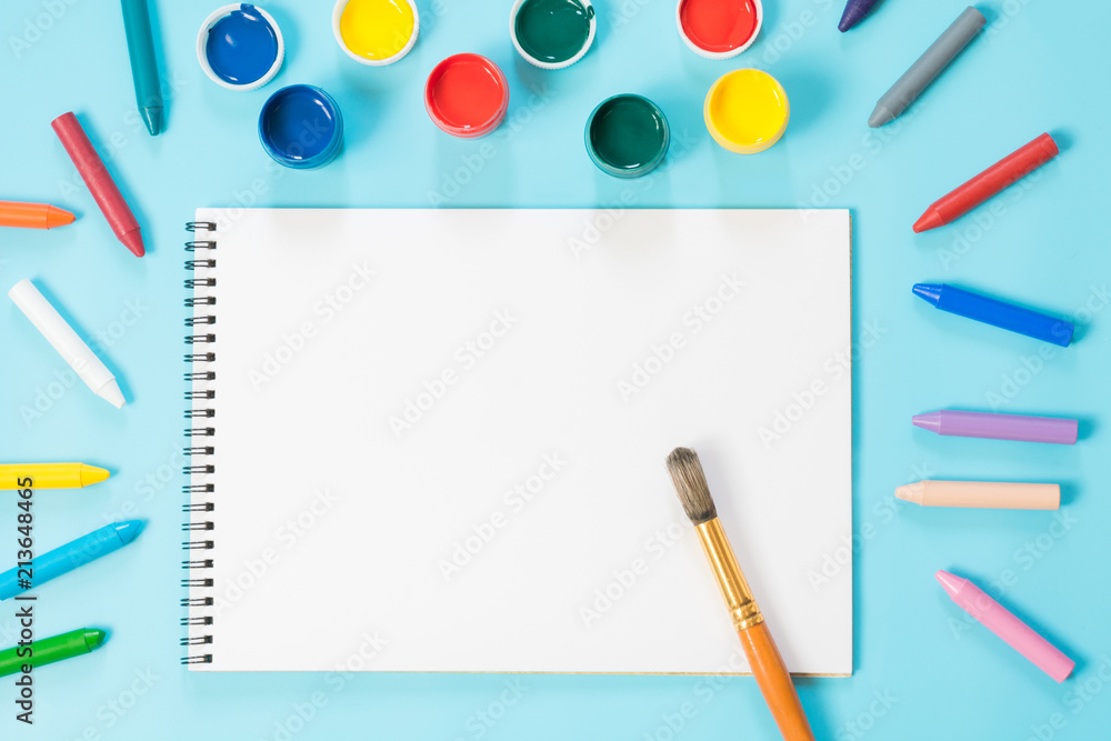 Back to school. Colorful paints, album and brush on punchy blue. Copy space. Top view. Back to school. Colorful paints, album and brush on punchy blue. Copy space. Top view.