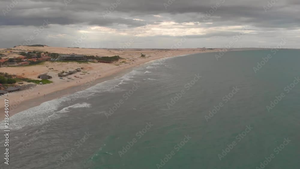 Beach in a cloudy day with wind turbines in the background in Canoa Quebrada, Ceará, Brazil Beach in a cloudy day with wind turbines in the background in Canoa Quebrada, Ceará, Brazil