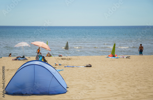 image of a camping tent on the almost deserted beach and the sea in the background