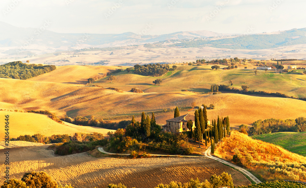 Italy. Pienza.  Beautiful Tuscany autumn rural landscape with cleaned fields and a farmhouse with cypress trees in the setting sun. Val d'Orcia natural Park