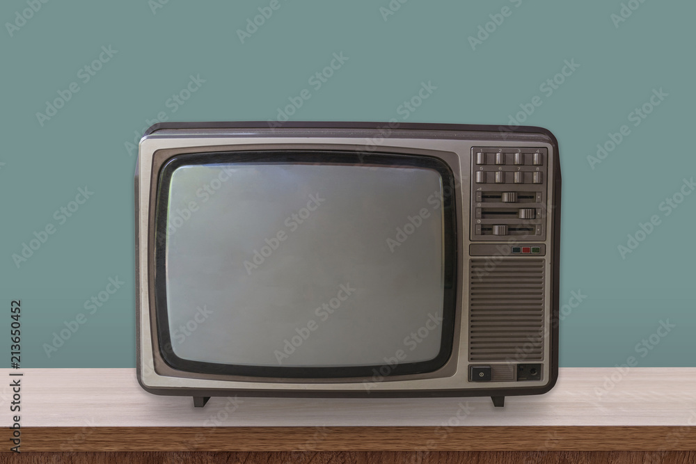 Vintage TV box on wooden table and pastel color background.