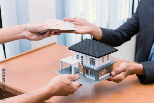 Business Real Estate Concept. House model in a hand and money.
