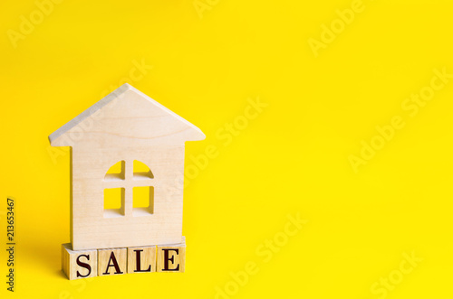 wooden house on a yellow background with the inscription "sale". sale of property, home, real estate. affordable housing. place for text. copyspace