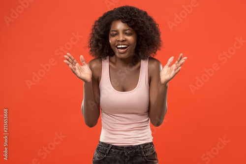The happy african woman standing and smiling against red background.