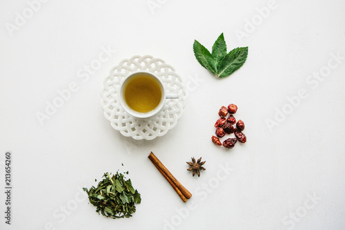A mug of fragrant and useful herbal tea. Nearby lie various ingredients for its preparation