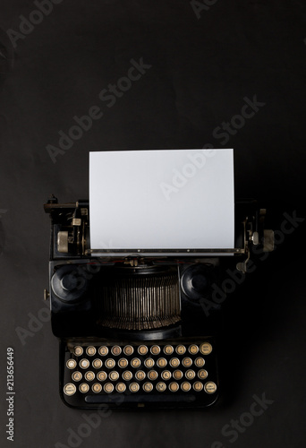 Vintage typewriter top down flatlay shot from above with empty, blank sheet of paper on black