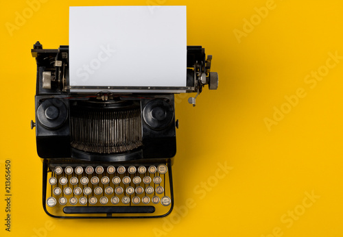 Vintage typewriter top down flatlay shot from above with empty, blank sheet of paper on yellow