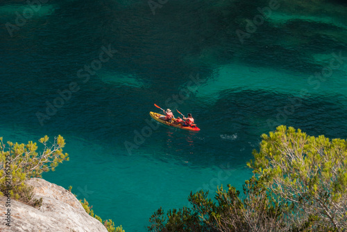 A family on a kayak in the sea of cove Macarelleta in Menorca