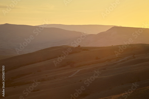 Scene of wild grandeur. Glorious spectacular sunrise in arid valley. Picturesque landscape with sun setting behind magnificent mountains in background. Beauty  nature  summer and traveling concept