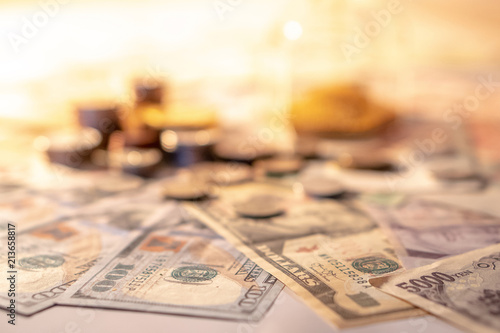 Various of international money coin and banknote with blurred hourglass in the background. Time investment with currency exchange concept. Focus on dollar banknote. photo