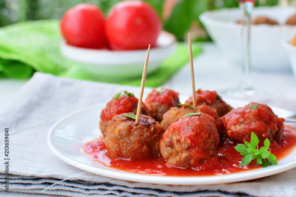 Meatballs in tomato sauce on white plate with greek basil herb Meatballs in tomato sauce on white plate with greek basil herb