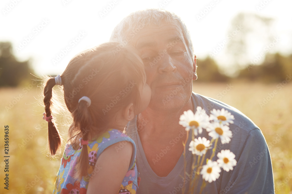 Joyful grandfather and granddaughter enjoy spare time together on green