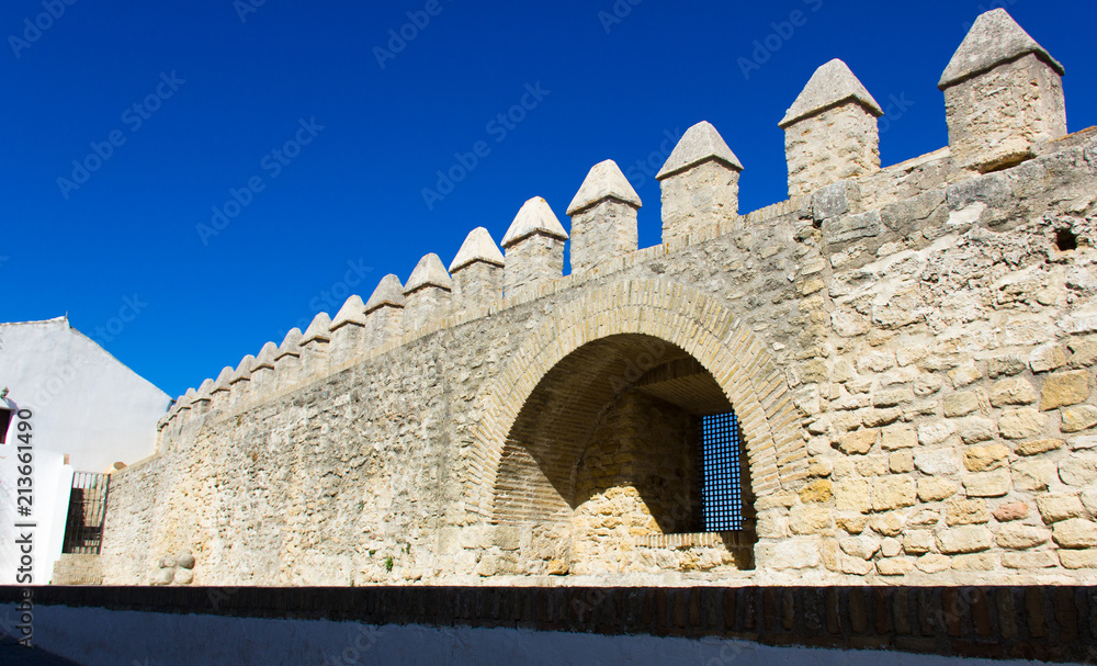 Rock wall of castle with window inside arc structure on sunny day in Vejer white town, Spain. Medieval architecture, fort, defense concepts