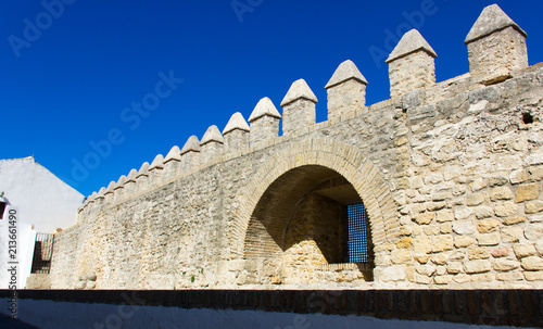 Rock wall of castle with window inside arc structure on sunny day in Vejer white town, Spain. Medieval architecture, fort, defense concepts
