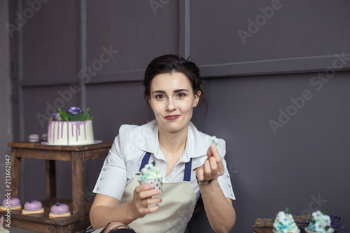 confectioner in a white apron on a pink background with a cake photo