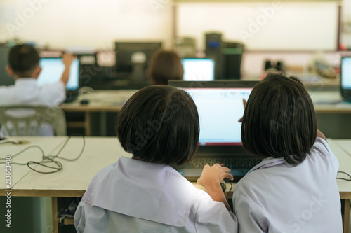 Primary Students study by computer in classroom.