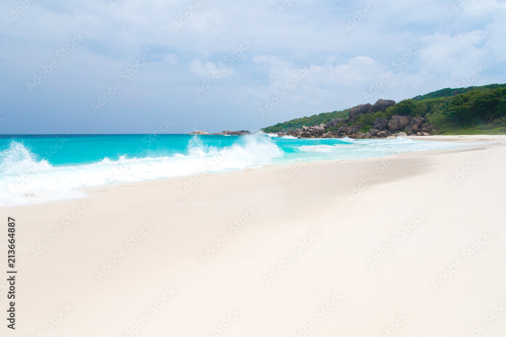 The beach on the Seychelles with white sand turquoise water and blue sky