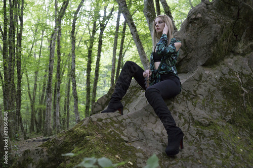 Fashion Model Girl on the Rock in the green summer forest